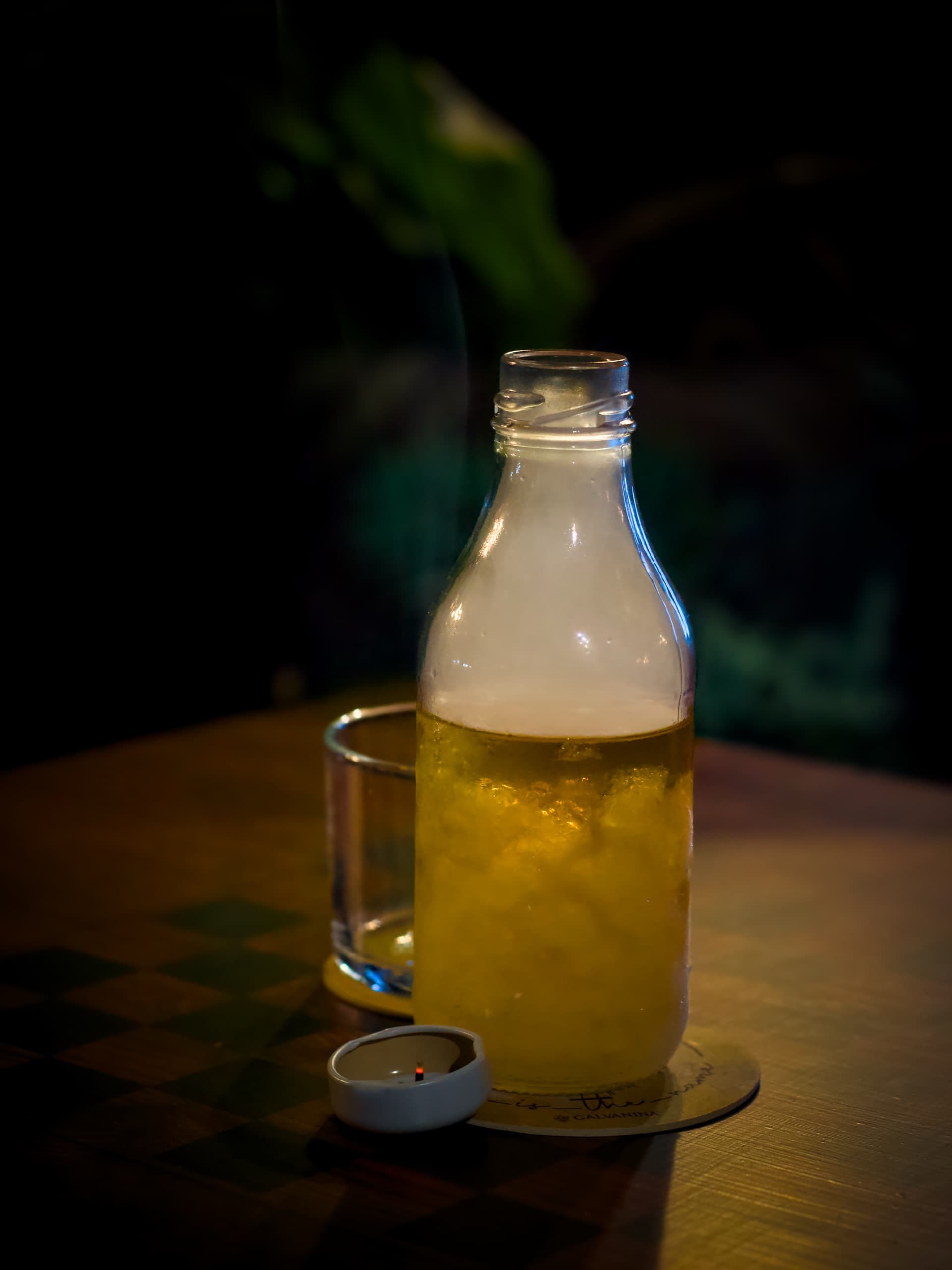 Cocktail dorato in bottiglia affumicata